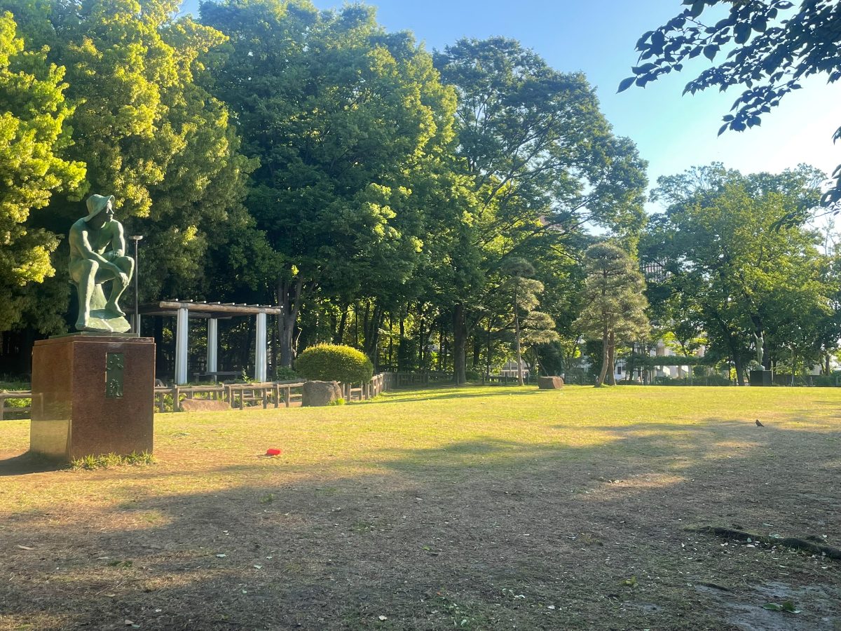 後谷公園 銅像と屋根付き休憩スペースが見える芝生広場