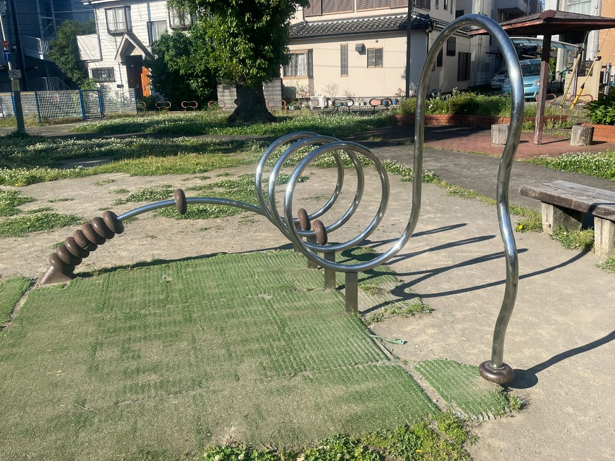 ステンレス製のスパイラル型でユニークな形状遊具。ベンチも隣接