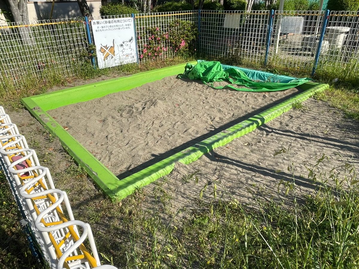 黄緑枠の広い砂場。猫除けネットカバー付きで衛生管理がされている