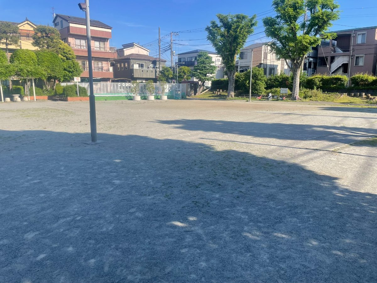 後谷第二公園の広い砂地広場全景。照明ポールと奥に遊具エリアが見える
